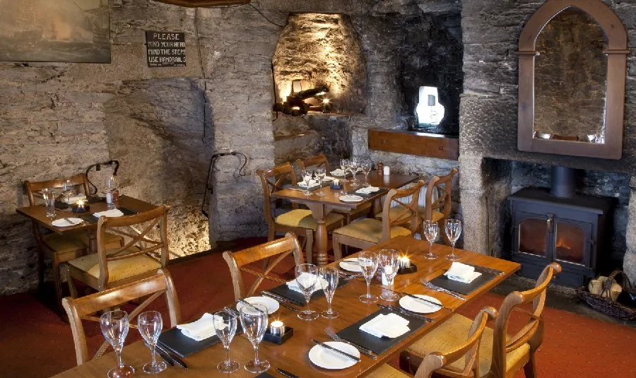 Tables laid in front of the lit wood-burning stove set into the stone wall