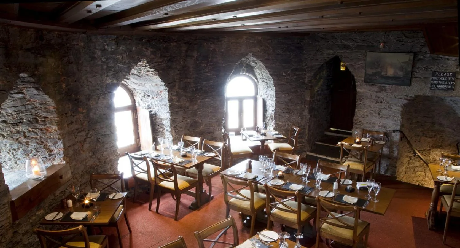 The dining room, bare stone walls, tables laid with white linen and candles